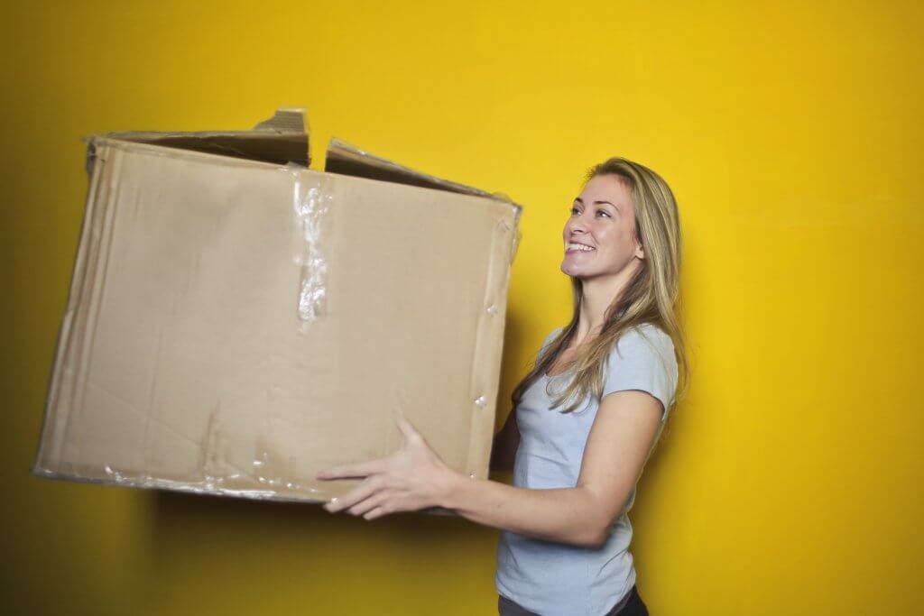 smiling woman holding decrepit cardboard box