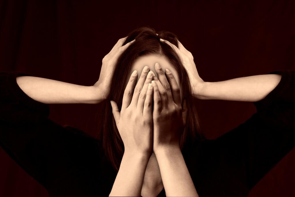 woman covering her face with another pair of hands holding her head