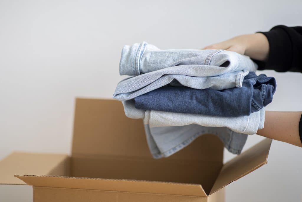 closeup of woman packing clothes into a cardboard box