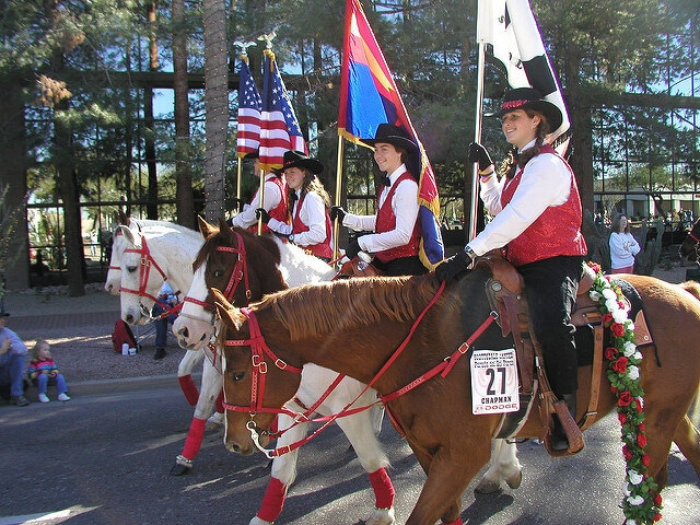 Parade of different flags adn women riding horses