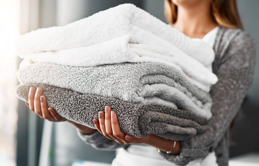 woman holding stack of folded towels