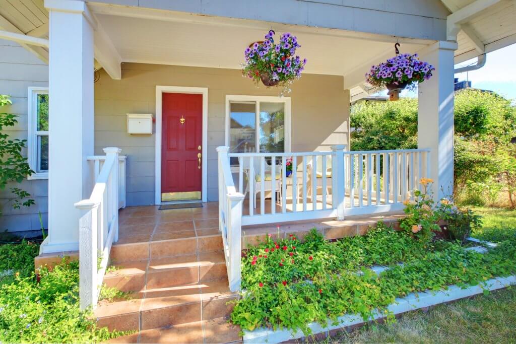 covered front porch with railing and hanging flower baskets