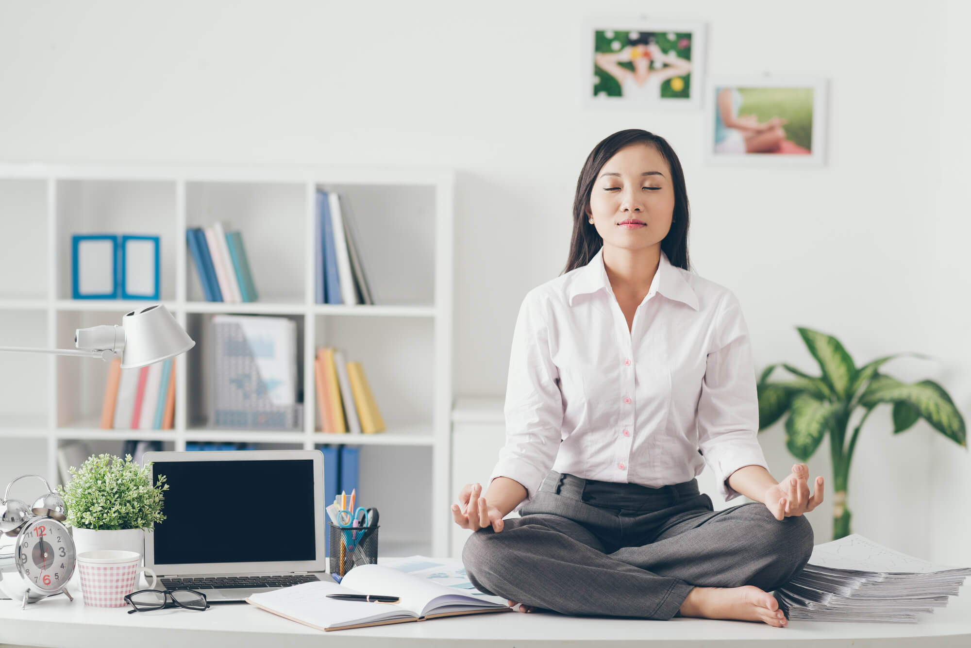 office move checklist- keep calm. Woman sitting on work desk doing meditation
