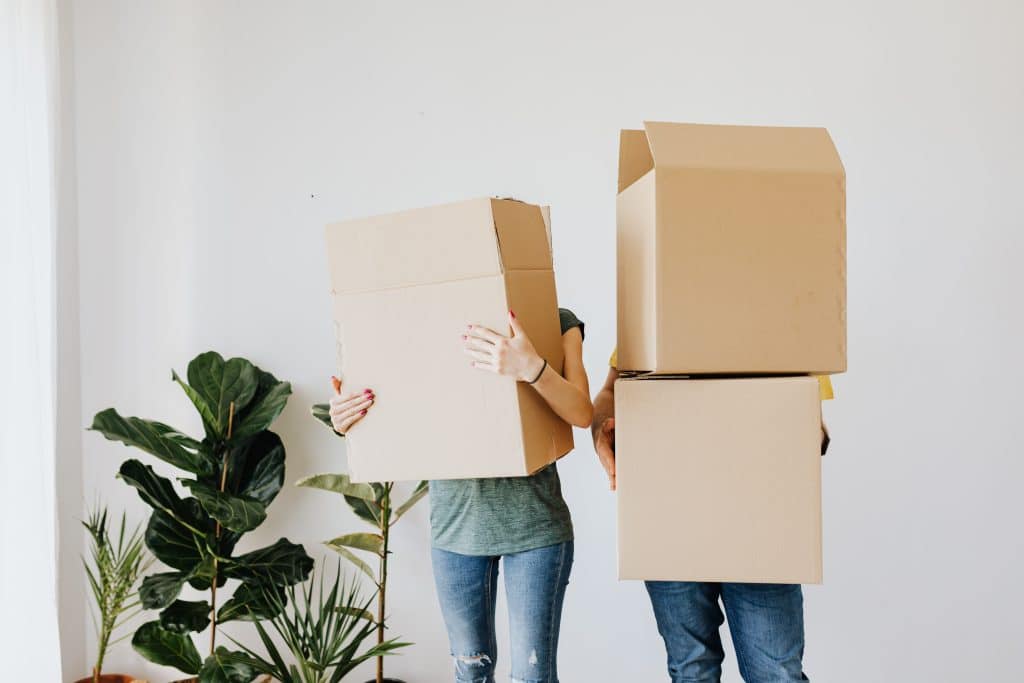 couple hiding faces behind moving boxes