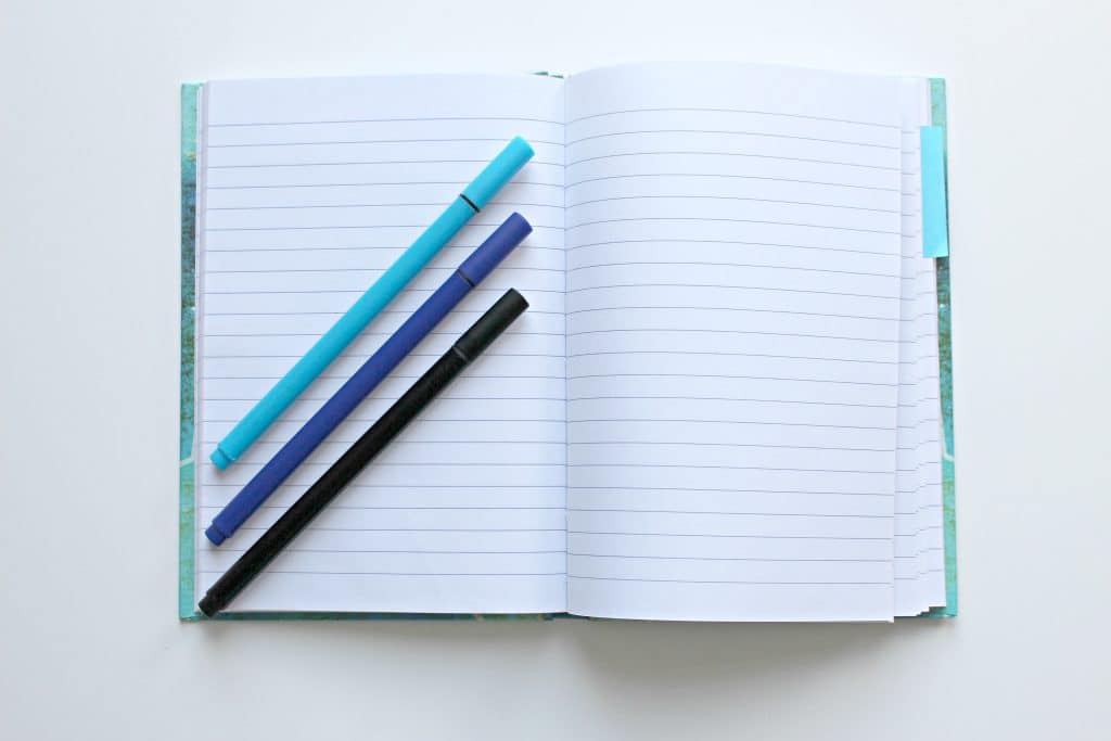 blue pens laying on open notebook