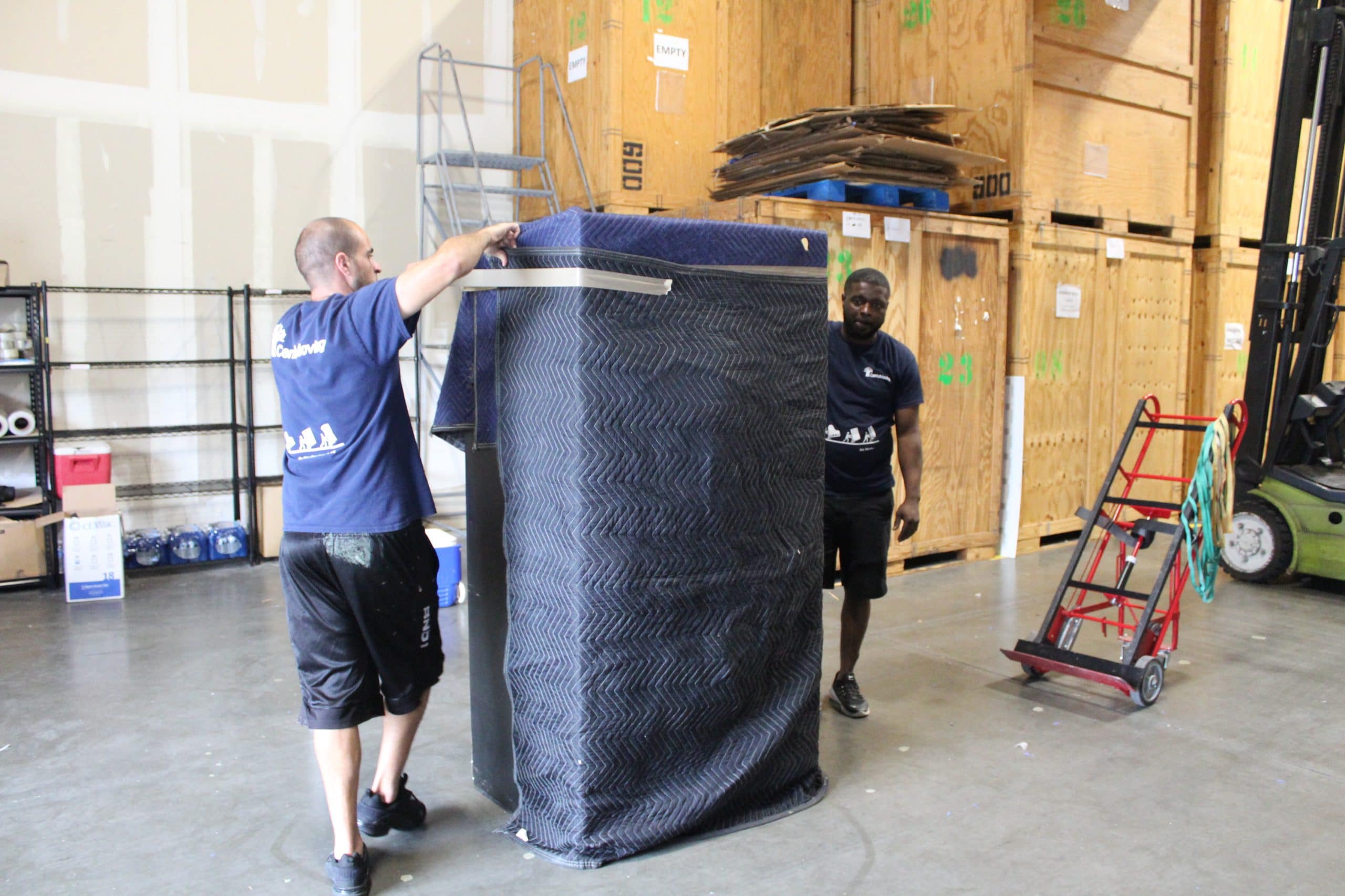 Men in a warehouse moving wrapped furniture