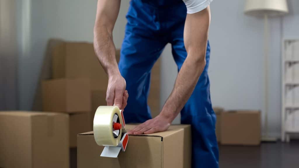 A mover tapes up a packed box