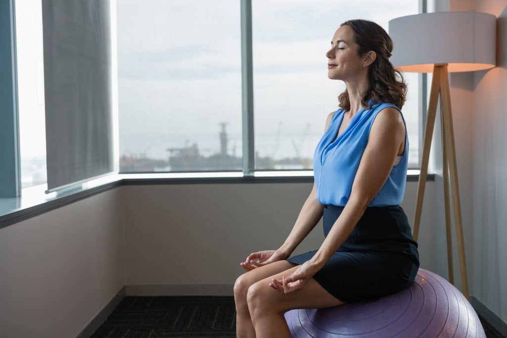 woman meditating on yoga ball in office